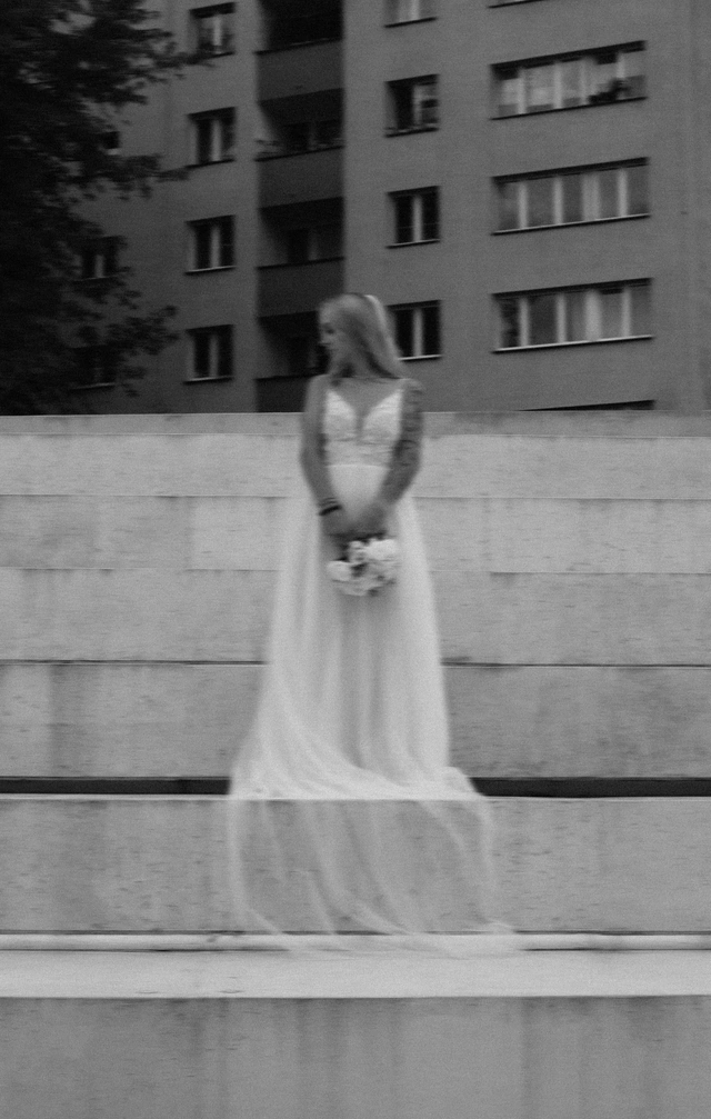 Fot. Karolina Zachurzok Czarno-biała fotografia panny młodej z welonem na miejskich schodach