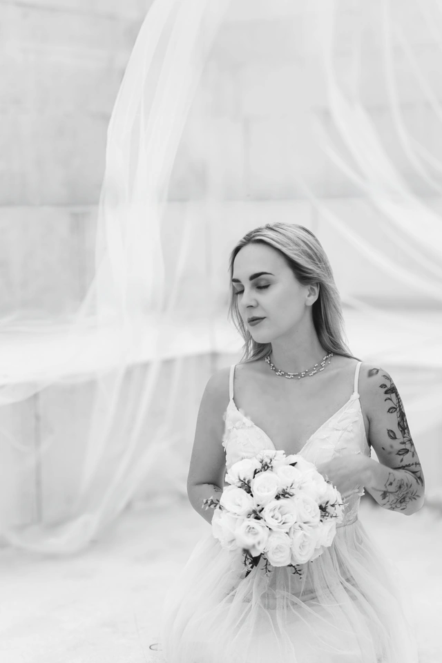 Fot. Małgorzata Drabina Czarno-biały portret panny młodej z bukietem i welonem w ruchu